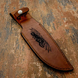 The handcrafted brown leather sheath showcases a dramatic engraving of a winged dragon in flight, its body coiling dynamically while its wings extend outward across the design.