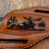 The engraving uses bold lines and shading to highlight the moose’s antlers and body structure while framing the scene with natural elements.