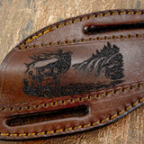 The artwork portrays a stag standing alert in a forest clearing with trees and mountainous terrain in the background.