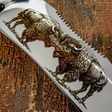 The blade is deeply engraved with a dramatic wildlife scene depicting two American bison locked in a powerful head-to-head stance.