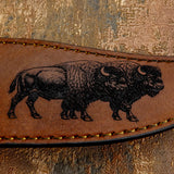 Brown leather strap with engraved bison design on a textured surface