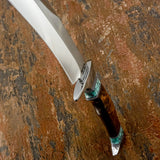 A close-up of a custom knife with a silver D2 blade, a dark brown handle, and turquoise inlay details