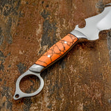 The handle features polished orange gemstone scales with contrasting dark veining. Stainless steel pins secure the scales to the full tang, while polished steel fittings frame the handle at both ends.
