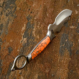 A tactical fixed-blade knife with a curved silver steel blade, a circular metal finger ring pommel, and an orange GemStone handle featuring a black crackle pattern 