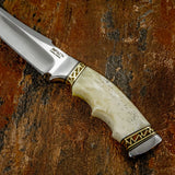 Closeup of the Sandstone knife handle, Ivory bone, slim profile, custom detailed brass firework.