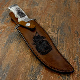 The handcrafted leather sheath features a dramatic shipwreck engraving presented in a layered above-and-below water composition.