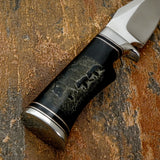 Fine engraved lines create detailed fur textures and subtle ground elements, giving depth and movement to the scene as it follows the natural curvature of the handle