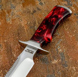 A close-up of a fixed-blade knife with a polished silver D2 blade and a red marbled Resin handle, Steel fittings