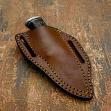 The knife is paired with a handcrafted brown leather sheath designed for durability and secure carry.