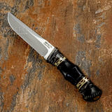A fixed-blade knife with a satin-finished D2 blade and a black handle featuring gold-toned geometric accents, UK knife shop