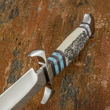 Different view of a custom bowie knife handle, showing an engraved camel bone handle with Gemstone inlays