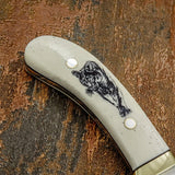 The handle is crafted from deeply engraved camel bone, showcasing detailed artwork of a cougar moving forward with focused intensity.
