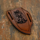 The handcrafted brown leather sheath complements the knife with a deeply engraved wildlife scene depicting a cougar resting along a rugged forest log,