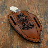 The engraving is centered along the sheath and framed by reinforced edge stitching, creating a rugged yet refined aesthetic suited for outdoor carry.
