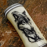The camel bone handle features a detailed wolf portrait engraving. A dominant wolf face is positioned above a smaller companion, suggesting a protective pack hierarchy
