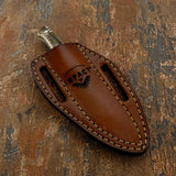A brown leather knife sheath with visible stitching and an embossed 'IMPACT' logo, holding a knife