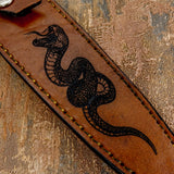 Deeply engraved serpent artwork on the front panel of the leather sheath
