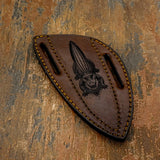 The handcrafted brown leather sheath features a deeply engraved depiction of a front-facing alligator emerging from the marsh