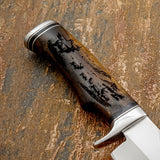 The handle is crafted from richly toned rosewood and features a deeply engraved wilderness scene portraying a majestic elk standing prominently while a small herd moves across the mountainside behind it