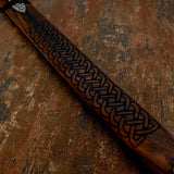 Wooden Scabbard of sword with intricate carvings on a textured brown background