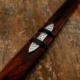 Wooden sword sheath with a silver blade guard on a textured brown background