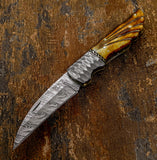 this exquisite custom folder showcases sculpted bone scales, Damascus blade, a hammered Damascus bolster