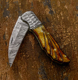 Folded knife with a damascus blade and carved camel bone handle
