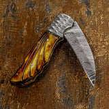 Foldable knife with a decorative blade and brown handle 