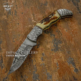 Handcrafted knife with decorative handle on a textured surface, branded 'Impact Cutlery Uk'.