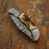 hand-forged Damascus steel blade with flowing pattern lines, sculpted Damascus bolsters, and a richly textured stag antler handle, UK knife store